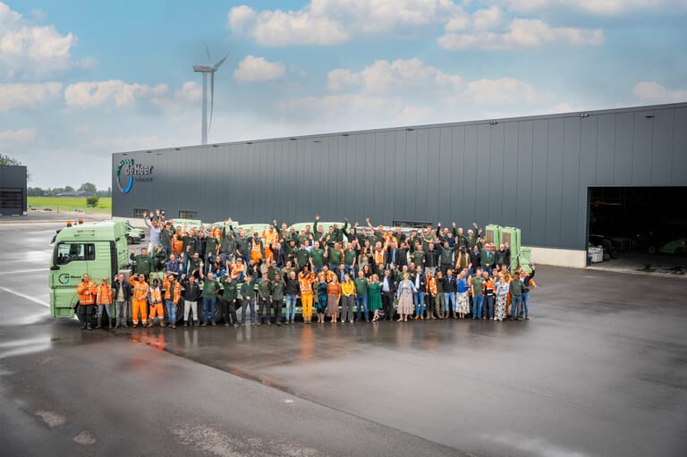 Een grote groep mensen voor en op een vrachtwagen op een industrieterrein