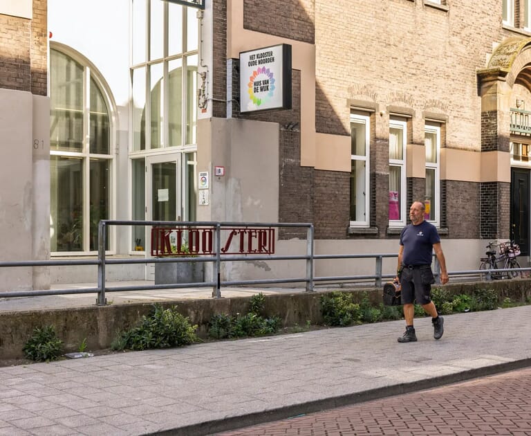 Man loopt langs een gebouw met opschrift 'Huis van de Wijk'.