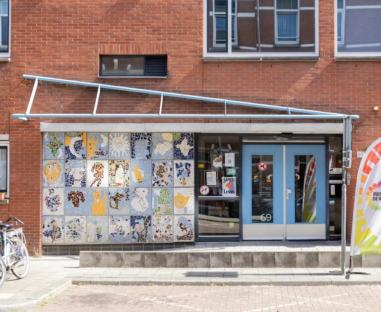 Voorkant van een gebouw met mozaïeken en een blauwe deur.