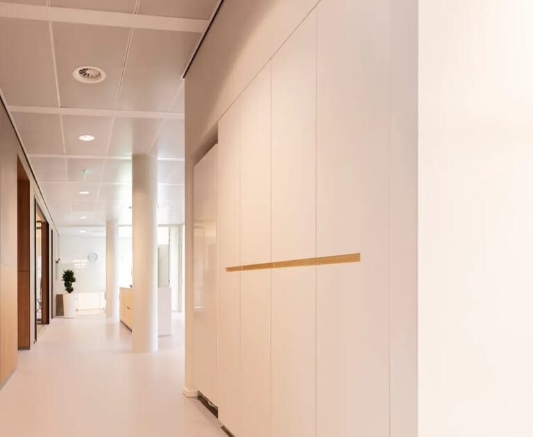 Verlichte kantoorhal met witte muren en moderne inrichting.