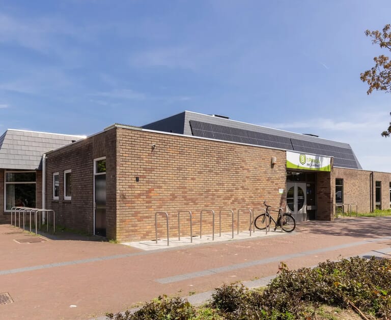 Bakstenen gebouw met fietsenrek en een fiets aan de ingang.