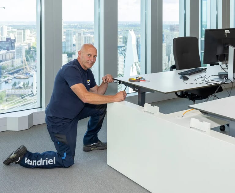 Man knielt bij bureau in modern kantoor met uitzicht op stad.