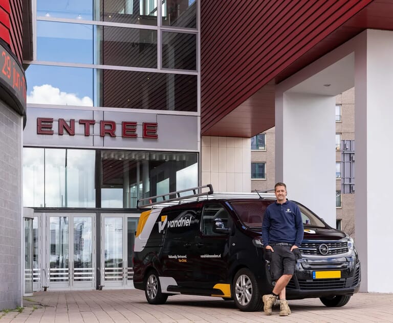 Man bij bedrijfsbusje voor een entree van een gebouw