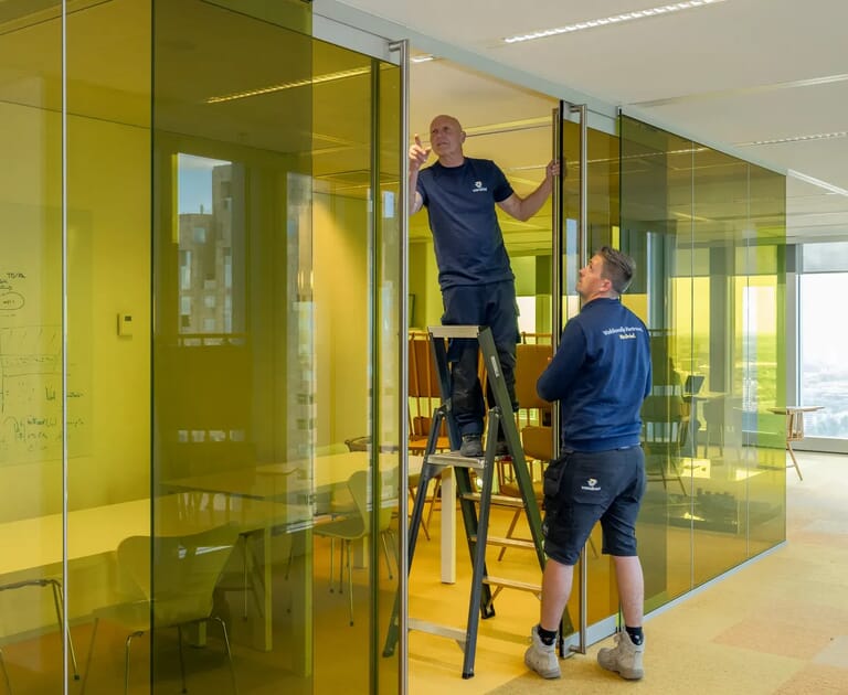Twee mannen installeren glazen wanden in kantoor.