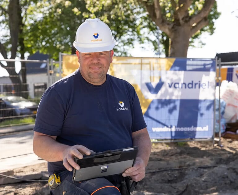 Bouwvakker met helm en tablet op bouwterrein