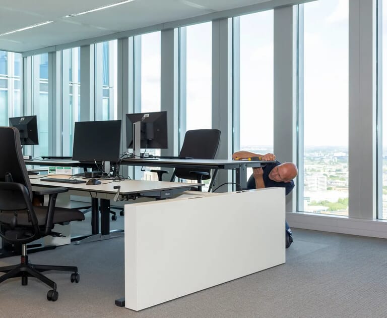 Man verstelt bureau in kantoor met grote ramen