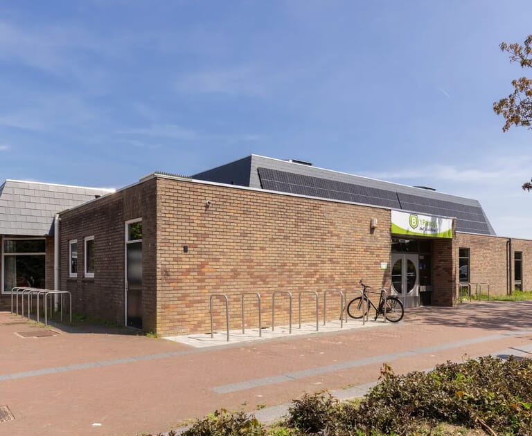 Bakstenen gebouw met fietsenrek en zonnepaneel op het dak