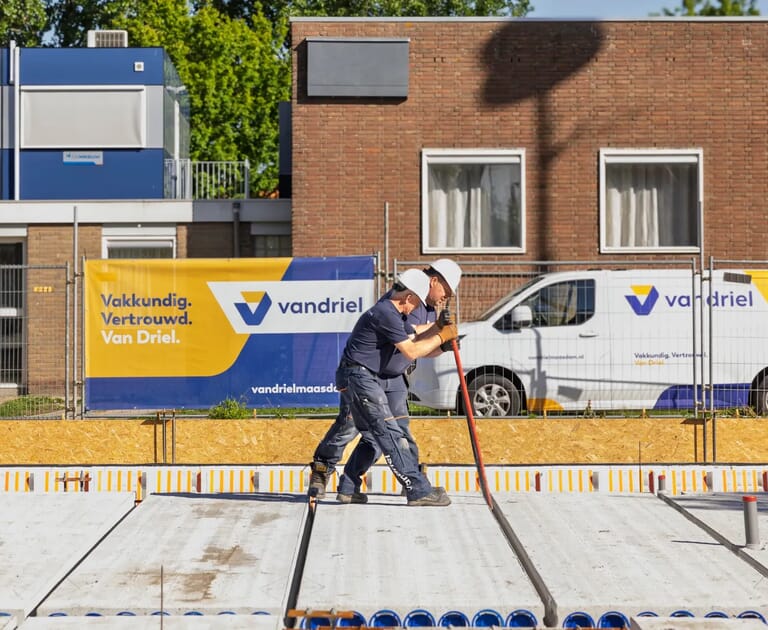 Twee bouwvakkers werken met gereedschap op een bouwplaats.