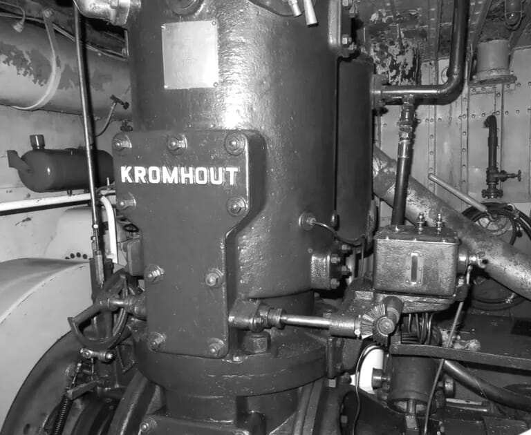 Close-up van een Kromhout scheepsmotor met pijpen en verbindingsstukken.