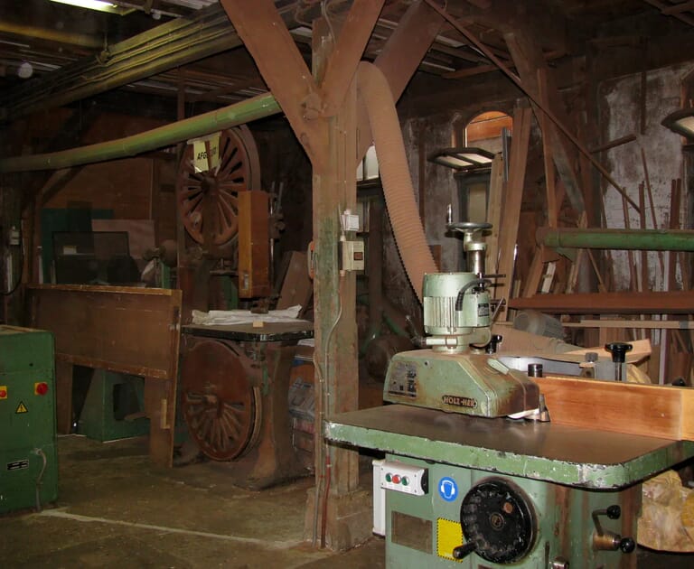 Interieur van een houtbewerkingsatelier met machines en gereedschap.