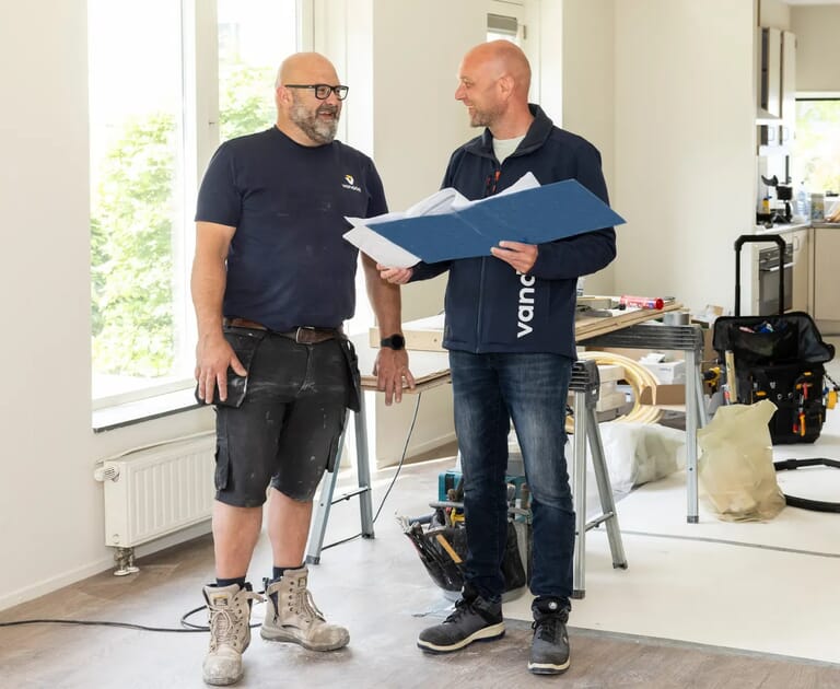 Twee mannen bespreken bouwproject in een kamer met gereedschap.