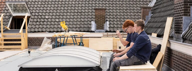 Twee mannen zitten op een dak tijdens een bouwproject.