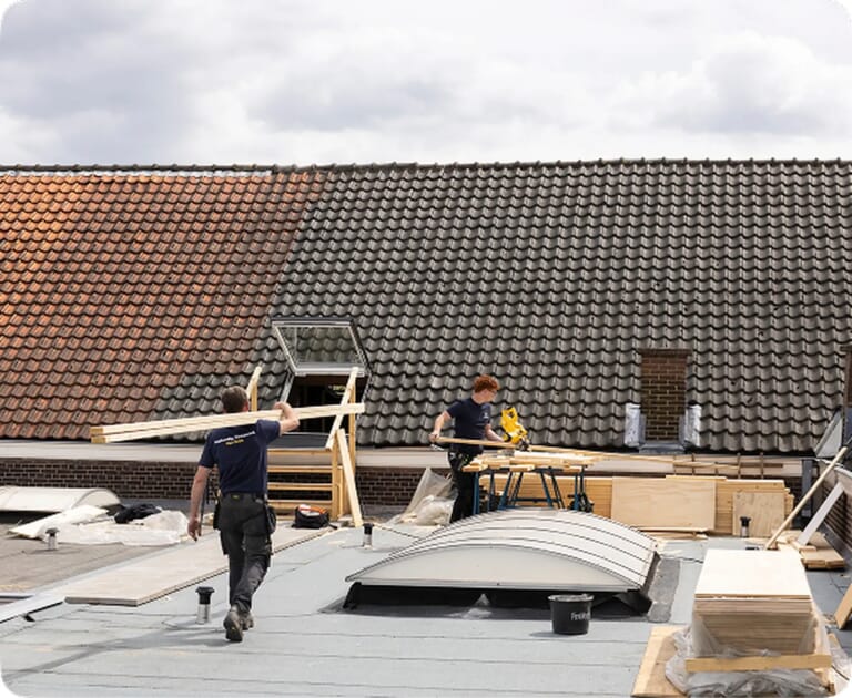 Twee mensen werken op een dak aan houtconstructie