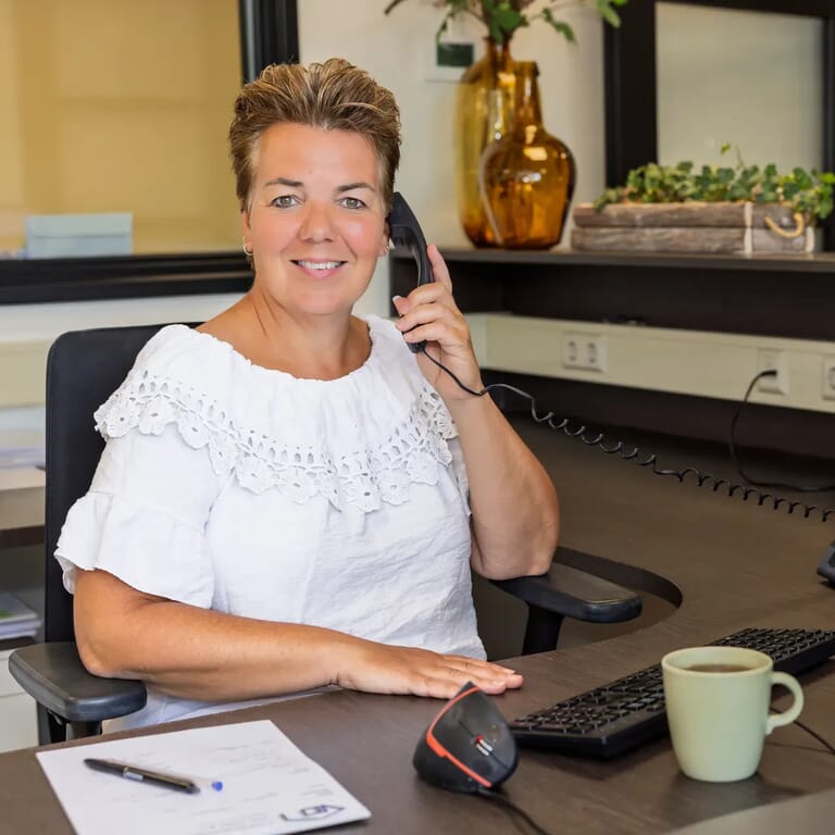 Vrouw in witte blouse aan het bellen op kantoor.