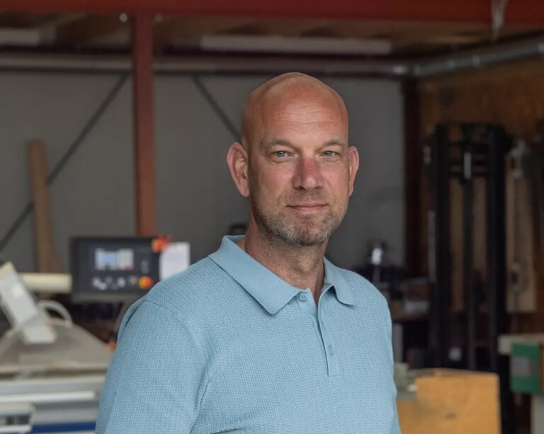 Man in een blauwe poloshirt in een werkplaats