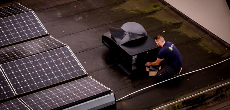 Man op een dak bezig met een installatie